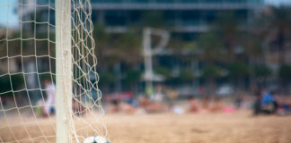 Un balón descansa dentro de las redes de un campo de fútbol playa.