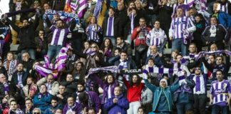 En la imagen se ve la grada del estadio Carlos Tartiere con varios aficionados del Real Valladolid portando banderas de hermanamiento con el Real Oviedo
