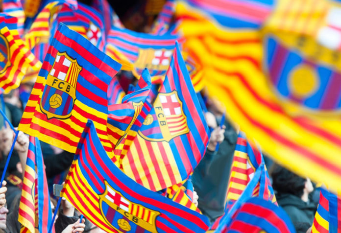Aficionados del FC Barcelona ondean banderolas con el escudo del conjunto catalán.