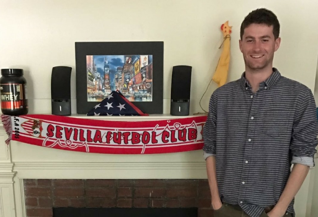 Chris Ulian posa junto a la boca de la chimenea de su habitación en la que colgó la bufanda del club andaluz. Sevilla FC